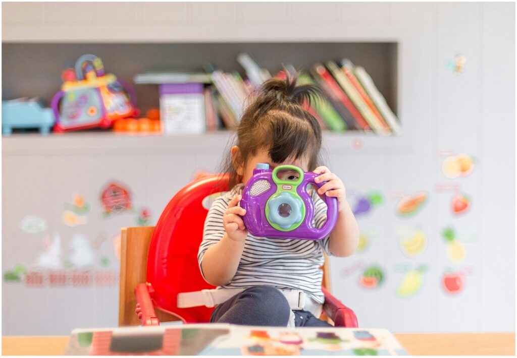 Child holding toy camera representing the question can late talkers catch up